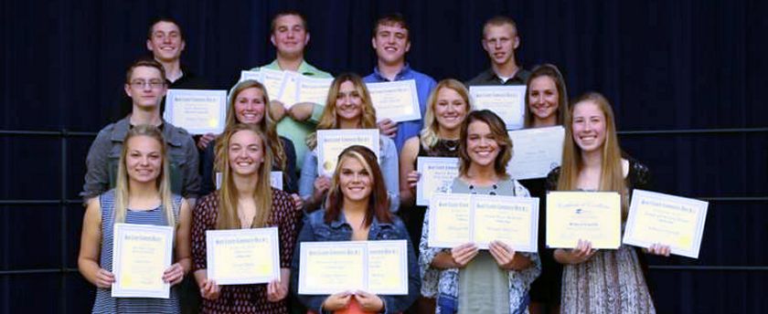 3 rows of standing high school boys and girls smile and hold scholarship certificates